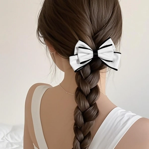 Elegant white leather bow hair tie with black trim shown on a braided hairstyle