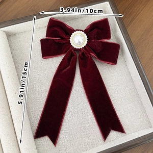 Detail view of burgundy velvet bow hair clip with faux pearl and gold bead center