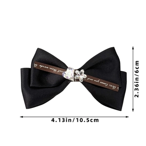 Detailed view of handmade black ribbon hair clip with brown printed bow and crystal charms