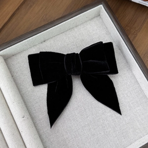 Detail of a vintage black velvet double-layered bow hair clip on a gray display tray