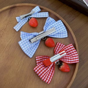 Lolita-Haarspangen mit rot-blauem Karomuster und Erdbeer-Anhängern auf einem Holztablett