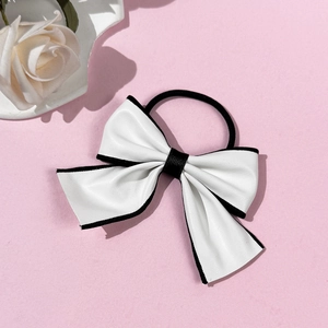 Detail of white leather bow hair tie with black trim and durable elastic band