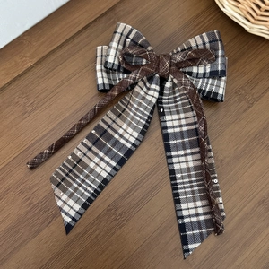 Détail du nœud à cheveux pied-de-poule avec paillettes sur rubans sur fond bois