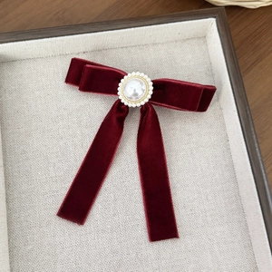 Macro detail of wine red velvet bow clip with elegant faux pearl and golden bezel