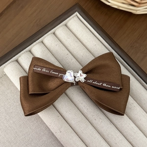 Detail of coffee brown matte satin bow hair clip with crystal heart and star embellishments