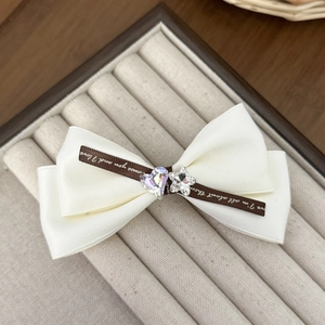 Elegant white satin bow hair clip with heart and star crystals in a jewelry box display