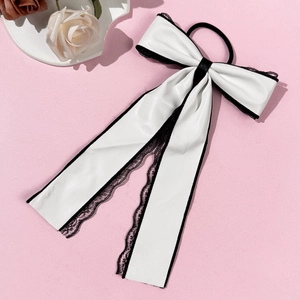 Detail of white faux leather bow hair tie with black lace trim on a pink background