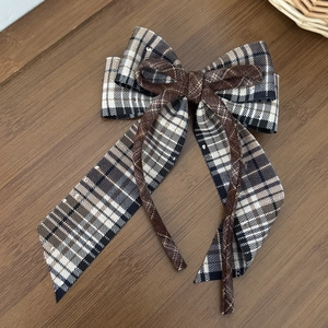 Détail de la pince à cheveux à carreaux avec cristaux et cordon brun sur fond de bois