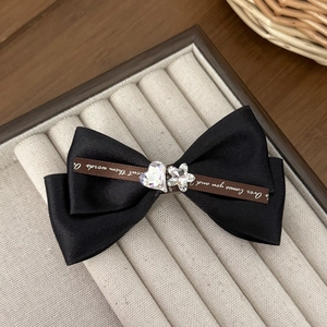 Detail of elegant black silk double-layer bow hair clip with crystal accents