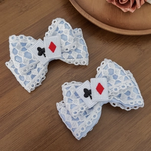 Detail of blue Lolita hair clips with white lace trim and embroidered card suits