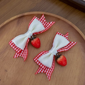Lolita-Haarspangen mit roten Karoschleifen und Erdbeeren auf einem Holztablett