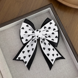 Detailed macro view of a handmade double-layer bow hair clip with black heart print pattern