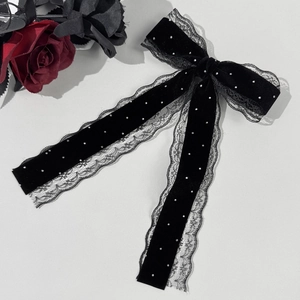 Detail of black velvet hair bow with delicate lace edges and sparkling rhinestones