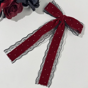 Detail of red velvet bow hair clip with black lace trim and sparkling rhinestones