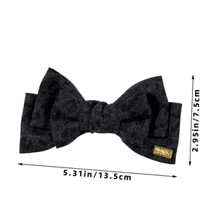 Detailed size view of black leopard print bow hair clip with golden metal tag