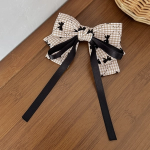 Detail of plaid bow hair clip with black ribbons on vintage dark wood background