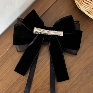 Elegant black velvet and mesh bow hair clip with long ribbon tassels on wood surface