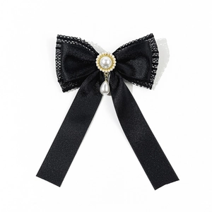Close-up of black lace bow brooch with white pearls and delicate golden metal base