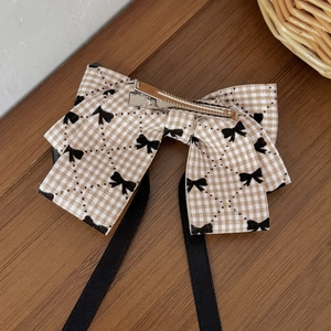 British style brown plaid bow hair clip with black ribbons on a vintage wooden desk