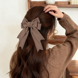 Detailed view of a large brown vintage bow hair clip on long wavy hair for autumn style