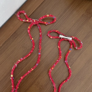 Set of two red knitted bow hair clips with colorful dots and long tassels