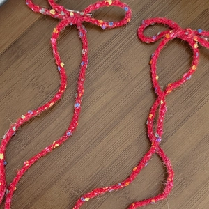 Detailed close-up of handmade red wool knit bow hair clips with colorful yarn flecks