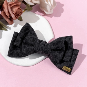 Detail of black velvet bow hair clip with a gold lucky metal plate on stone tray