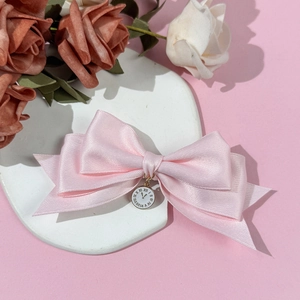 Eleganter rosa Satin-Haarclip mit Schleife und Vintage-Uhrenanhänger auf Stein