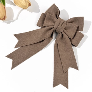 Close-up of a large dark brown bow hair clip with elegant long ribbons on white background