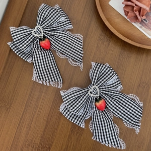 Detail of strawberry lace bow hair clips with heart buckle on rustic wood surface