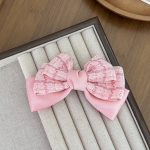 Vue macro détaillée de la pince à cheveux en tweed rose et satin sur un plateau