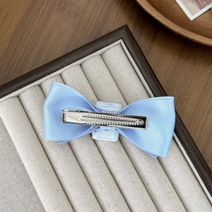 Light blue satin bow hair clip with silver metal alligator clamp on velvet display