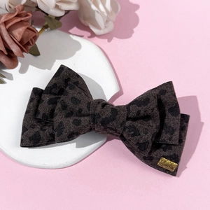 Vintage leopard print bow hair clip with Lucky gold tag on white display ceramic plate