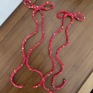 Close-up of red crochet bow hair clips with colorful polka dots and long curly yarn tassels