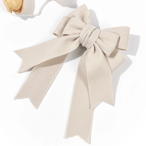 Detail of elegant cream bow hair clip featuring soft wool texture and long ribbons