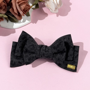 Close-up of a leopard print bow hair clip with a golden rectangular metal buckle detail