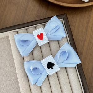 Detail of light blue satin bow hair clips with poker heart and spade embroidery