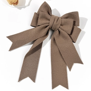 Detail of a large brown fabric bow hair clip with elegant long ribbons and fabric texture