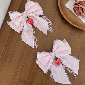 Sweet pink plaid bow hair clips with lace trim and strawberry pendants on wood table