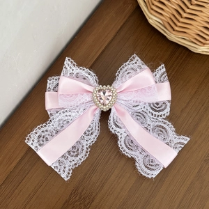 Detail van roze kant harik strik met een hartvormige strass en parel in het midden