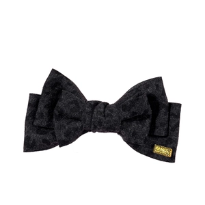 Classic black leopard print bow hair clip with a refined gold metal tag on white background