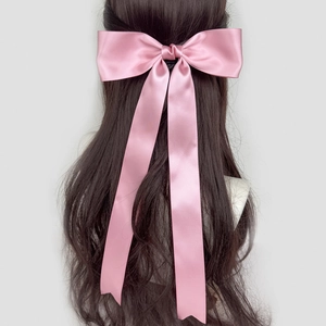 Dettaglio di un fiocco per capelli in raso rosa con lunghi nastri di seta