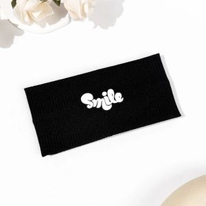 Detailed view of black knitted sports headband with white Smile letters and ribbed texture