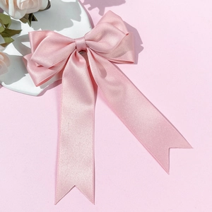 Detail view of a pink satin ribbon hair bow with long streaming ribbons and silky texture