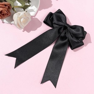 Detail of elegant black satin ribbon hair bow showing delicate fabric texture and long tails