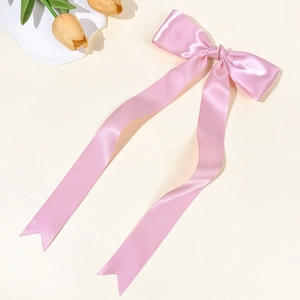 Dettaglio di un fermaglio per capelli con fiocco in raso rosa e lunghi nastri