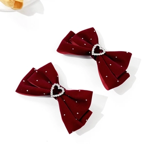 Detailed macro of wine red velvet bow hair clips with heart-shaped rhinestone centers