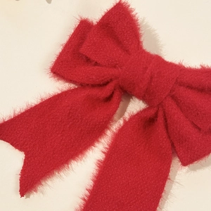 Close-up of a large red plush bow hair clip with soft fuzzy texture and elegant design
