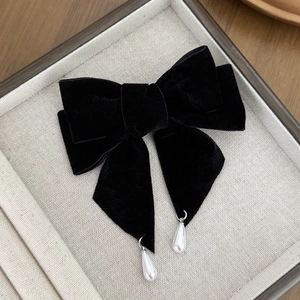 Detail of a black velvet bow hair clip featuring two elegant white teardrop pearl pendants
