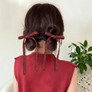 Detail of red knitted bow hair clips with long ribbons on double bun hairstyle
